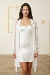 Woman wearing a white satin nightgown with a lace cover-up in a minimalistic room.