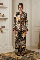 Woman in a patterned outfit standing in a stylish room with decor elements.