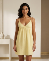 Woman wearing a yellow nightgown in a minimalistic room.