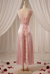 Mannequin wearing a pink lace dress with red ribbons against a draped curtain background.