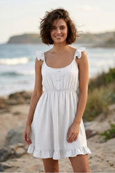 Woman in a white dress standing on a beach with ocean in the background