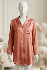 Mannequin wearing a pink satin nightshirt with floral and candle decorations in the background.