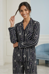 Woman wearing a navy floral pajama set in a room with a light blue chair.