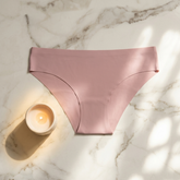 Pink underwear on a marble surface with a candle
