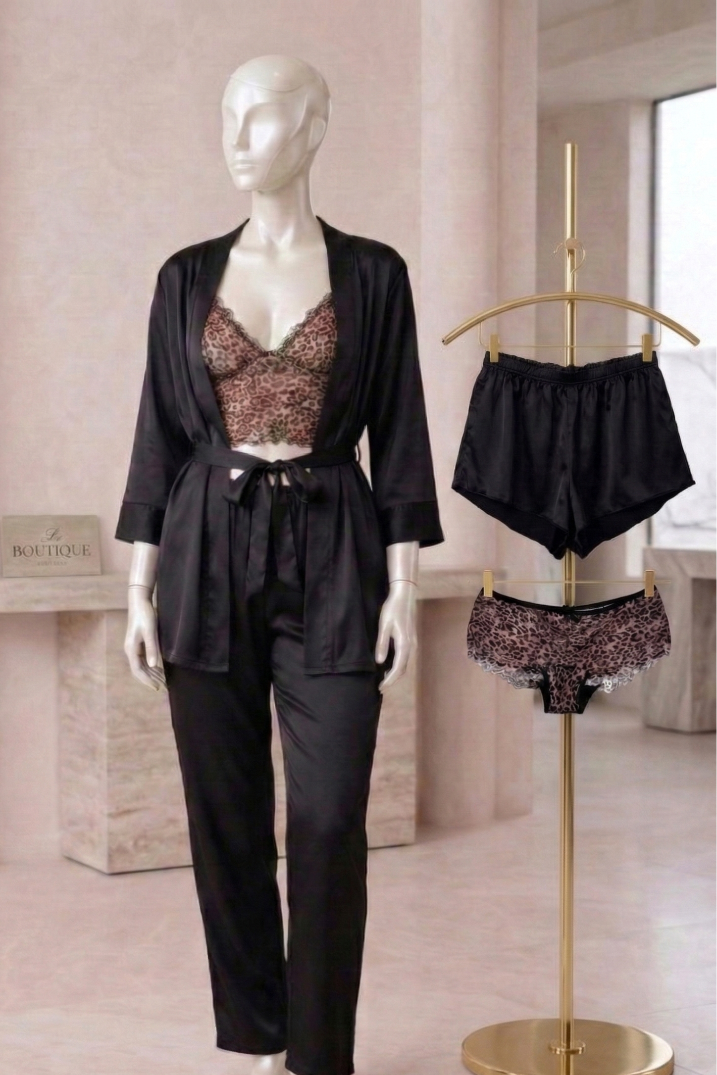 Mannequin wearing a black outfit with matching pants and top, standing next to a gold hanger with additional black and patterned underwear.