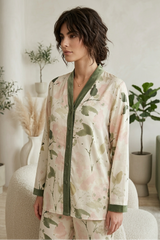 Woman wearing a floral pajama set in a cozy room with plants.
