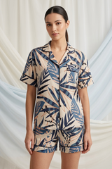 Woman wearing a tropical leaf patterned romper against a draped fabric background