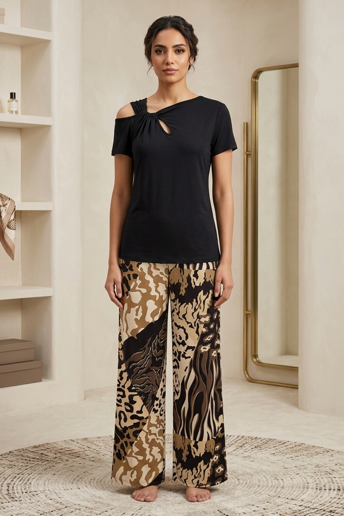 Woman wearing a black top and patterned pants standing in a room with shelves and a mirror.