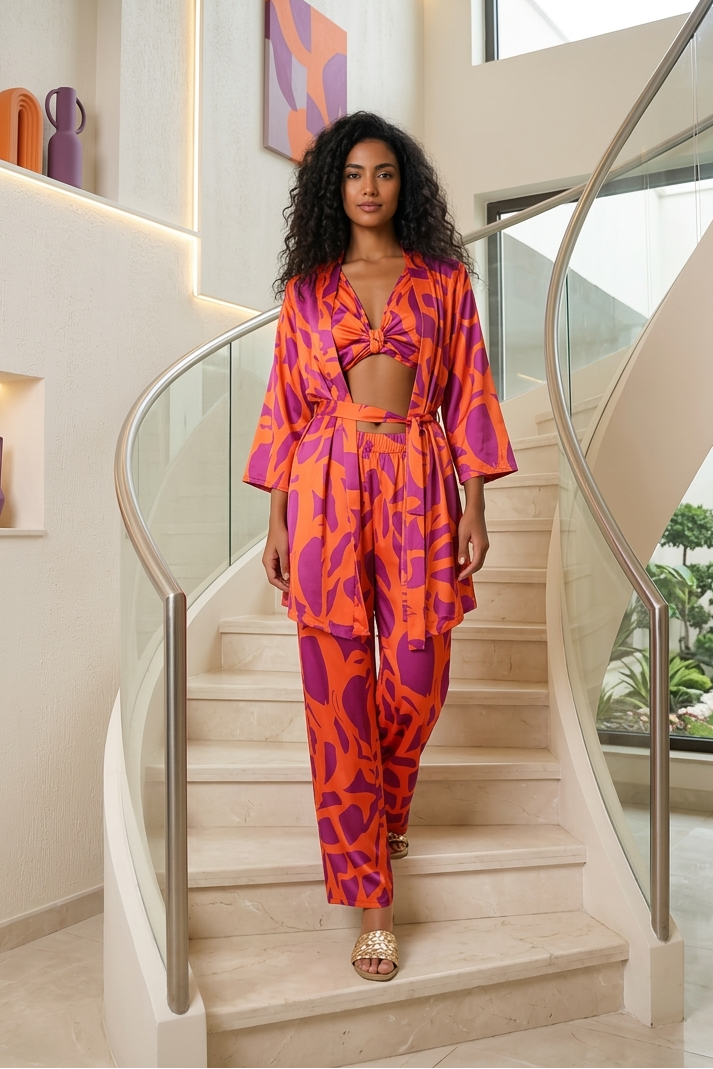 Woman in a vibrant orange and purple outfit standing on a staircase in a modern home.