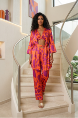 Woman in a vibrant orange and purple outfit standing on a staircase in a modern home.