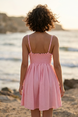 Woman in a pink dress standing on a beach with ocean view