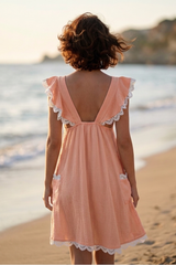 Woman in a peach dress standing on a beach with ocean view