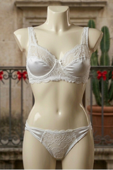 Mannequin wearing a white lace bra and panties set with a decorative background.