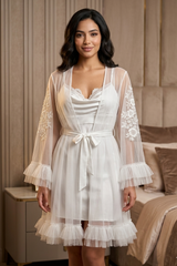Woman wearing a white lace nightgown with sheer sleeves in a bedroom setting.