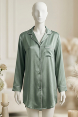 Mannequin wearing a green satin nightshirt with floral and candle decorations in the background.
