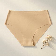 Beige women's underwear on a light gray background with a small flower arrangement.