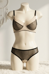 Mannequin wearing a black bra and panties set on a white surface with a dreamcatcher in the background.