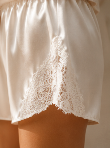 White satin shorts with lace trim on a neutral background