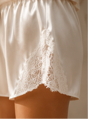 White satin shorts with lace trim on a neutral background