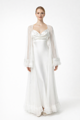 Woman wearing a white satin gown with sheer sleeves on a white background